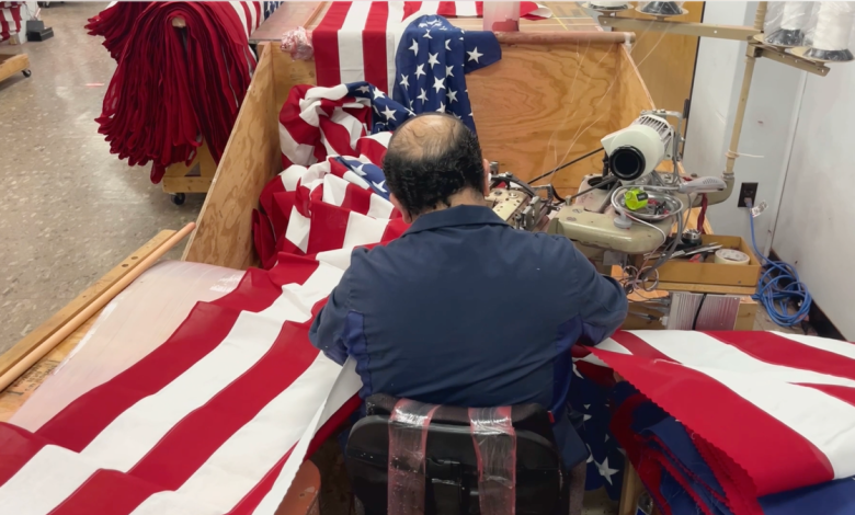 Man sewing the top section of red and white stripes to the bottom half of an American flag at Allied Materials.